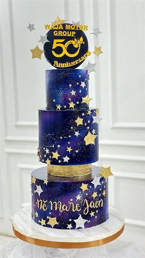 Kue anniversary Waja Motor Group ke-50 berwarna biru malam dengan bintang emas dan perak
