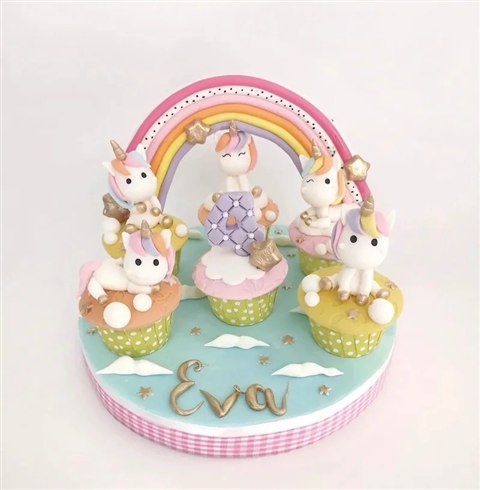Set cupcake unicorn putih bersurai pastel dengan pelangi besar, angka empat dan tulisan Eva pada alas turquoise