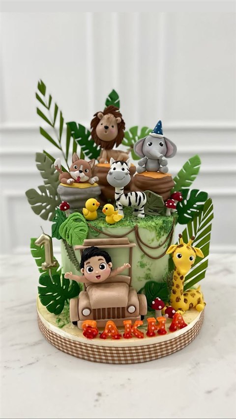 Kue safari hijau dengan anak di jeep serta singa, gajah, zebra, dan jerapah.