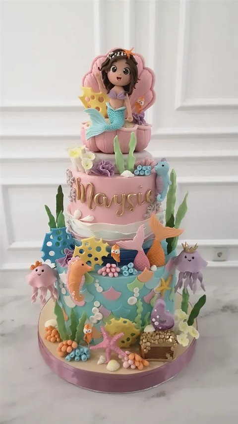 Kue mermaid Maysie dengan figur putri duyung, kerang pink, ubur-ubur dan peti harta