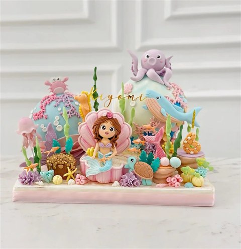 Dua kubah piñata pastel dengan putri duyung di kerang serta gurita, paus, dan penyu.